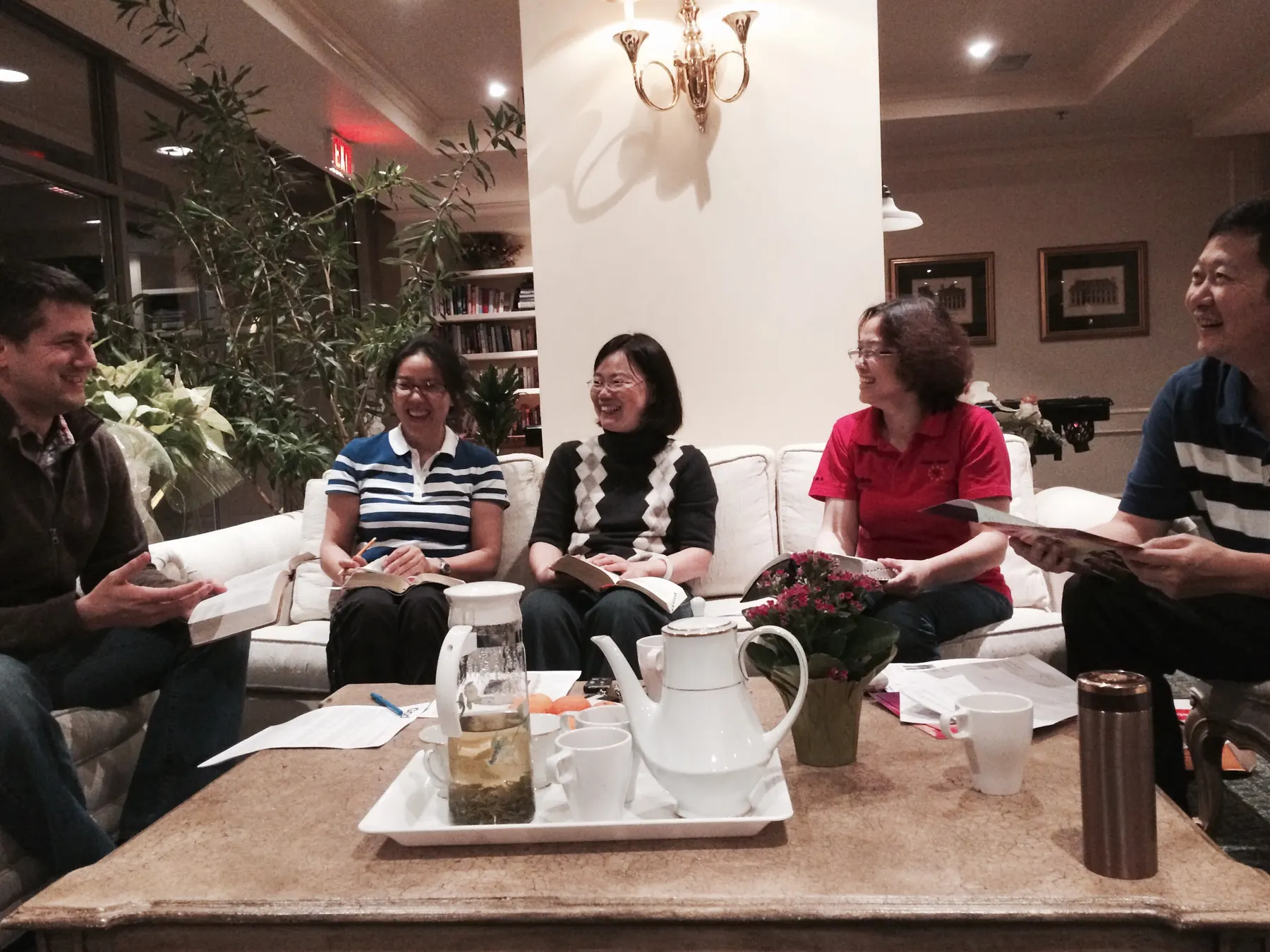 A small fellowship gathers in a home with open Bibles and coffee